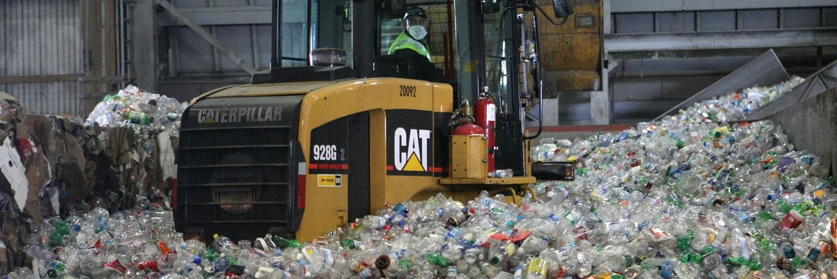 A tractor drives through a giant pile of plastic bottles