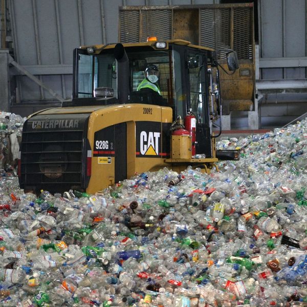 A tractor drives through a giant pile of plastic bottles