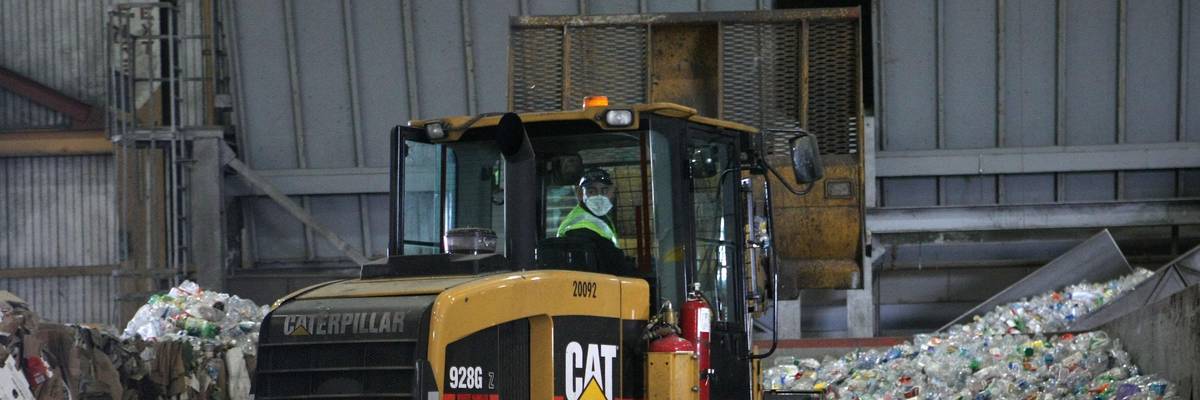 A tractor drives through plastic bottles at a recycling center in San Francisco, California.