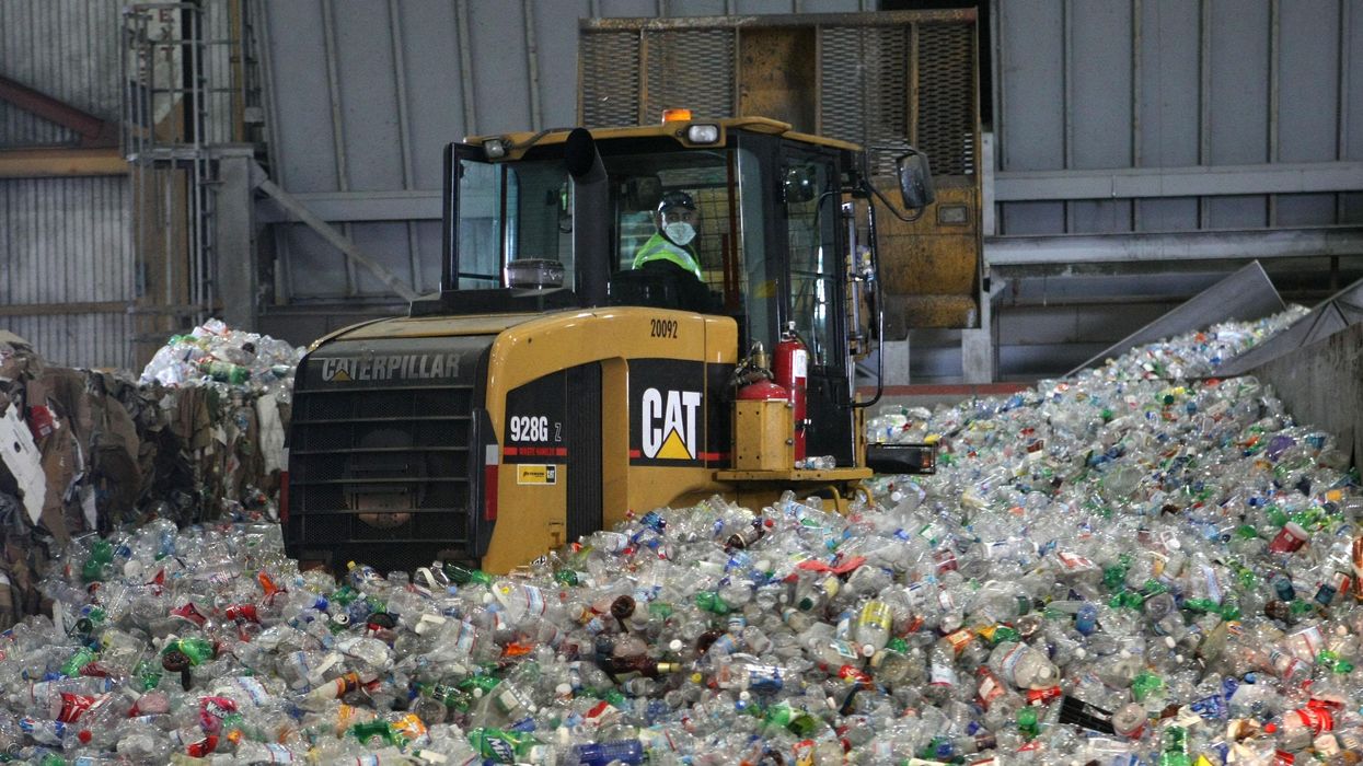 A tractor drives through plastic bottles at a recycling center in San Francisco, California.