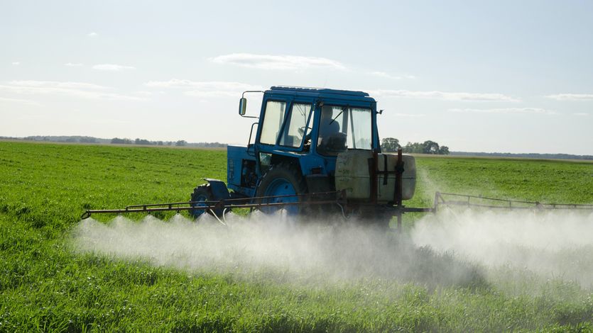 A tractor sprays pesticides in a field 