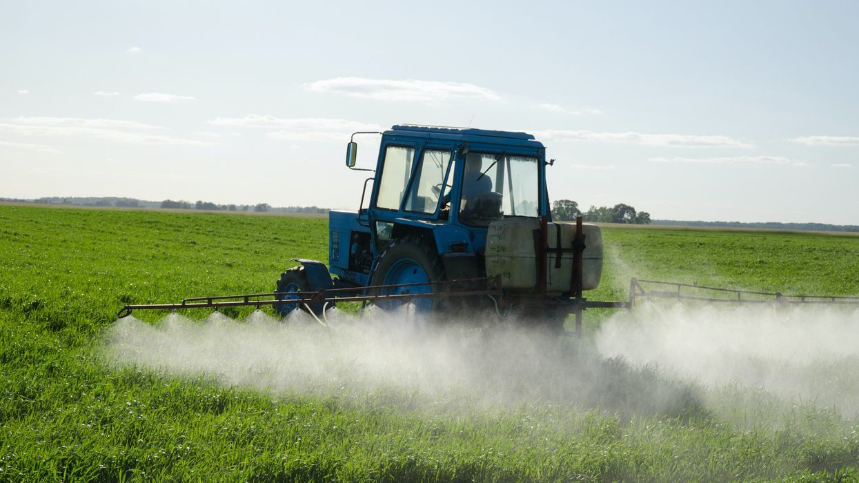 A tractor sprays pesticides in a field