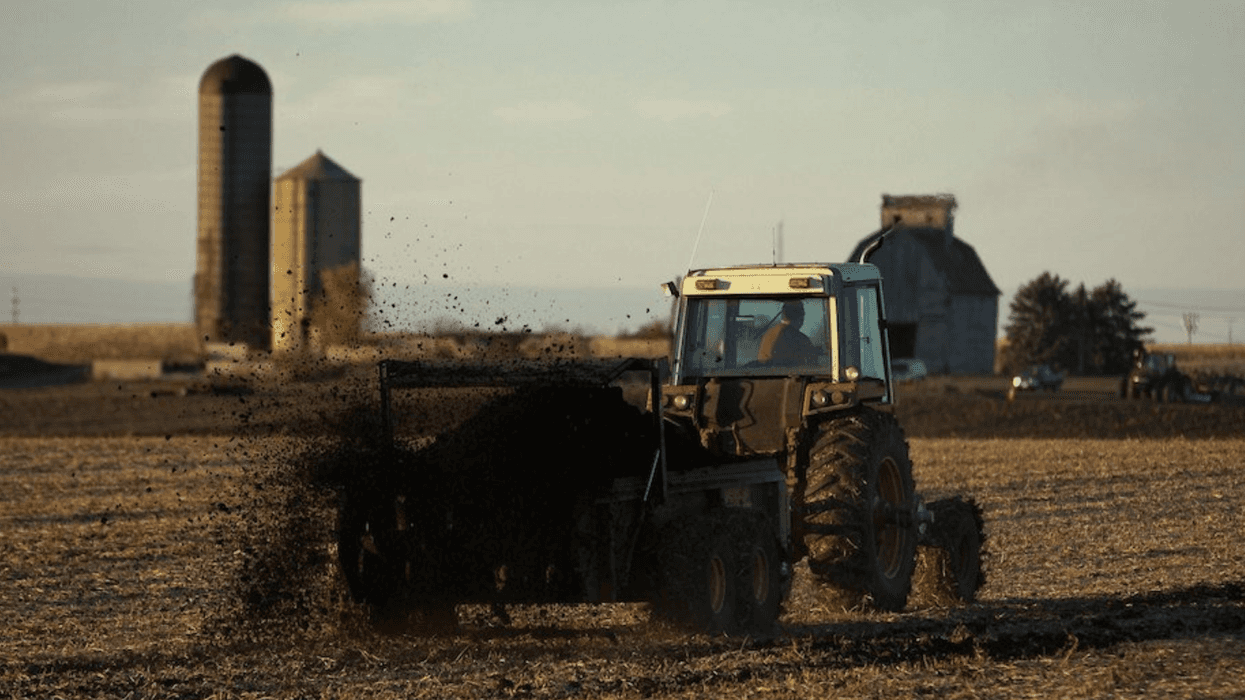 A tractor spreads sewage sludge-based fertilizer in a field