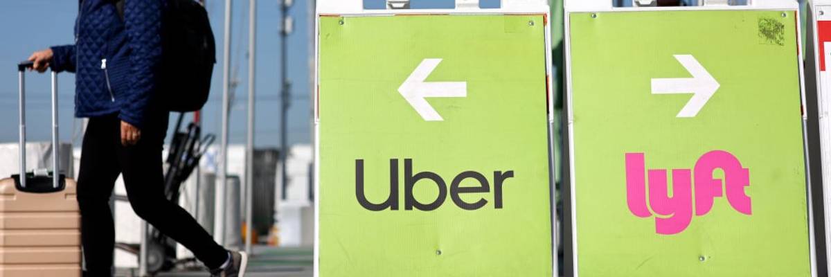 A traveler walks past an Uber-Lyft rideshare sign.
