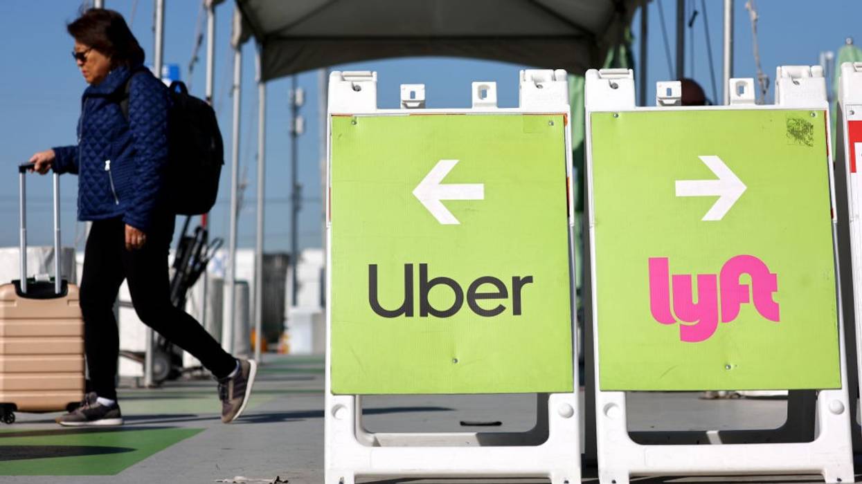 A traveler walks past an Uber-Lyft rideshare sign.
