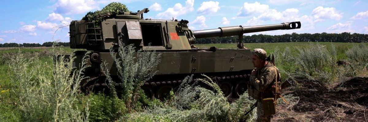 A Ukrainian marine walks past a M109 155mm self-propelled howitzer