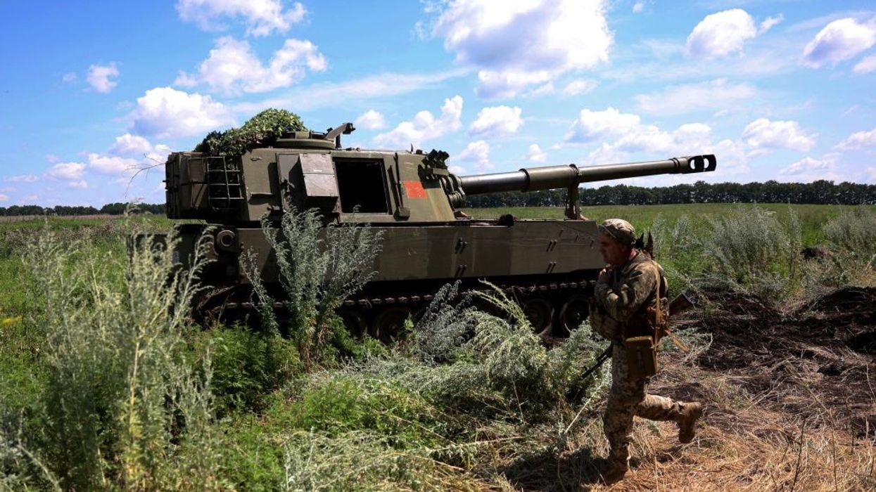 A Ukrainian marine walks past a M109 155mm self-propelled howitzer