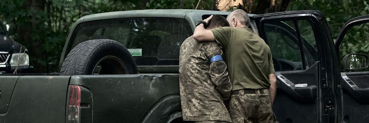 A Ukrainian soldier cries on his comrade's shoulder