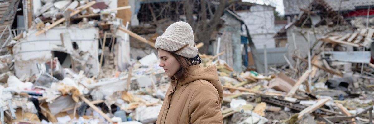 A Ukrainian woman stands amid the ruins of homes