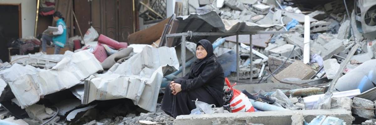 A veiled, elderly Palestinian woman sits amid the rubble of her home in Gaza