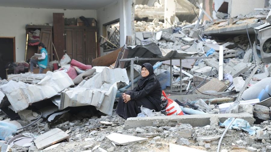 A veiled, elderly Palestinian woman sits amid the rubble of her home in Gaza
