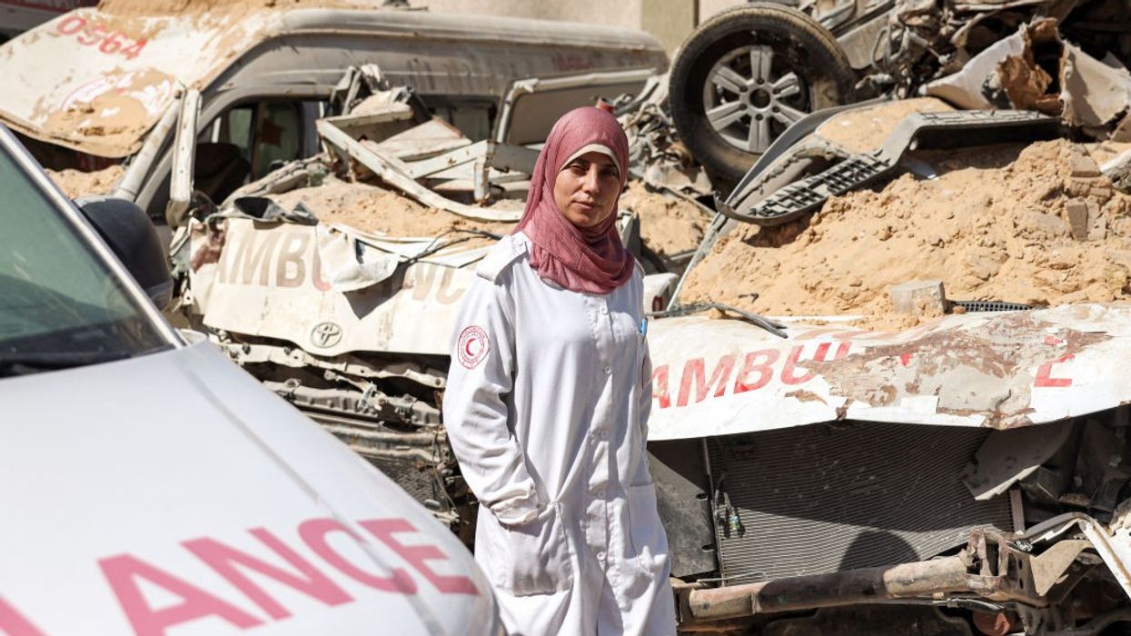 A veiled female Palestinian Red Crescent paramedic walks by a row of bombed ambulances in Gaza