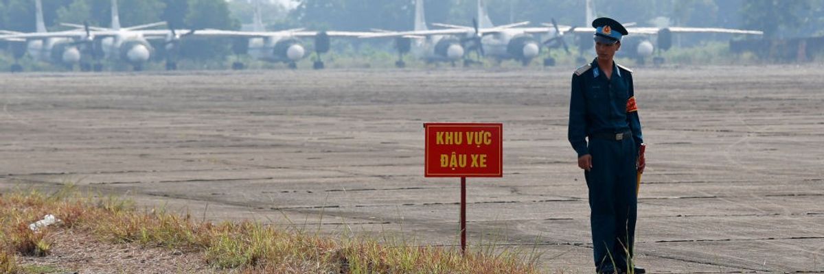 A Vietnamese soldier stands news to a hazardous warning sign