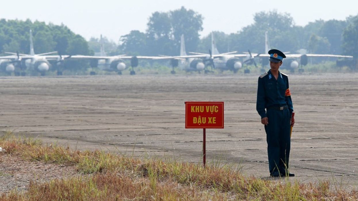 A Vietnamese soldier stands news to a hazardous warning sign