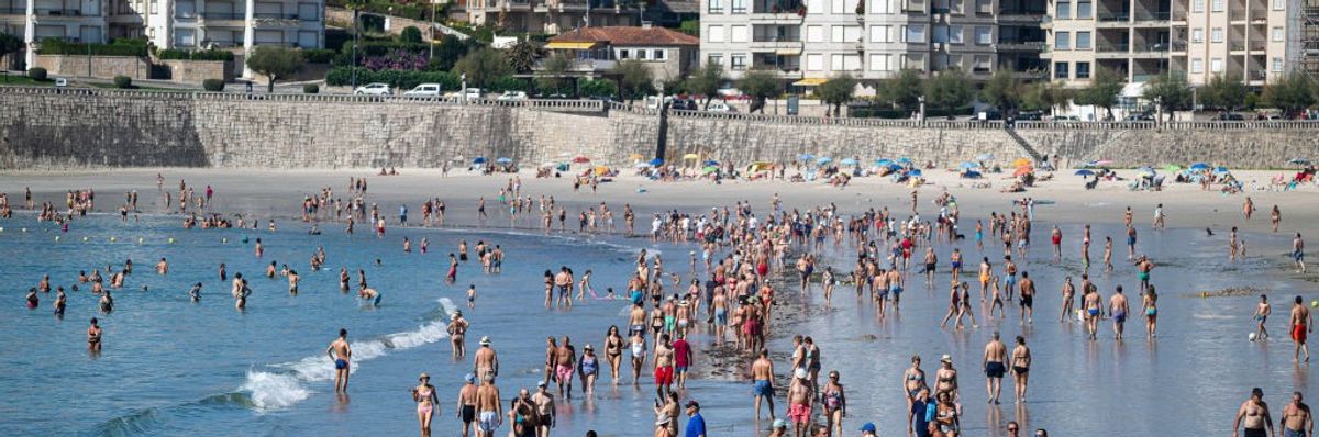 A view of a crowded beach with buildings in the background.