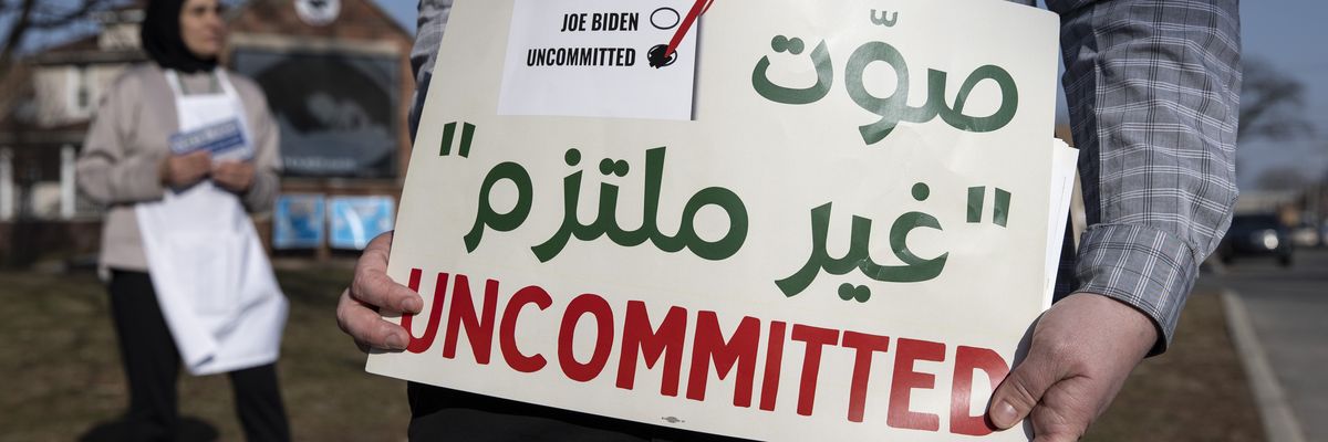 A volunteer with the Listen to Michigan campaign holds a sign reading, "Uncommitted"