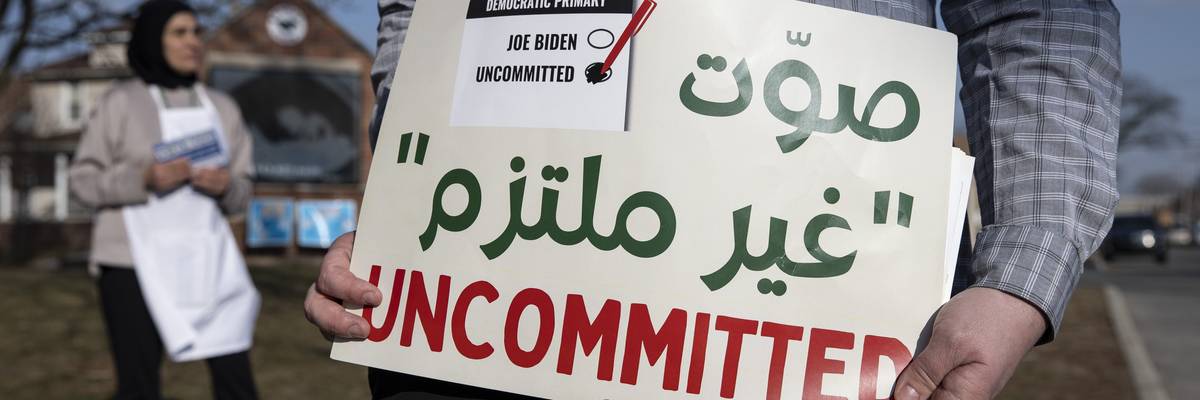 A volunteer with the Listen to Michigan campaign holds a sign reading, "Uncommitted"