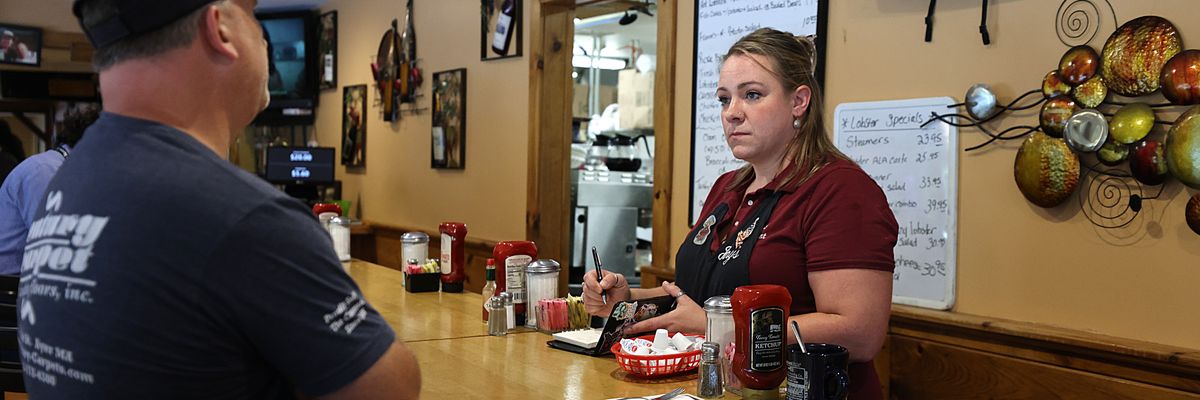 A waitress serves a customer at a counter.