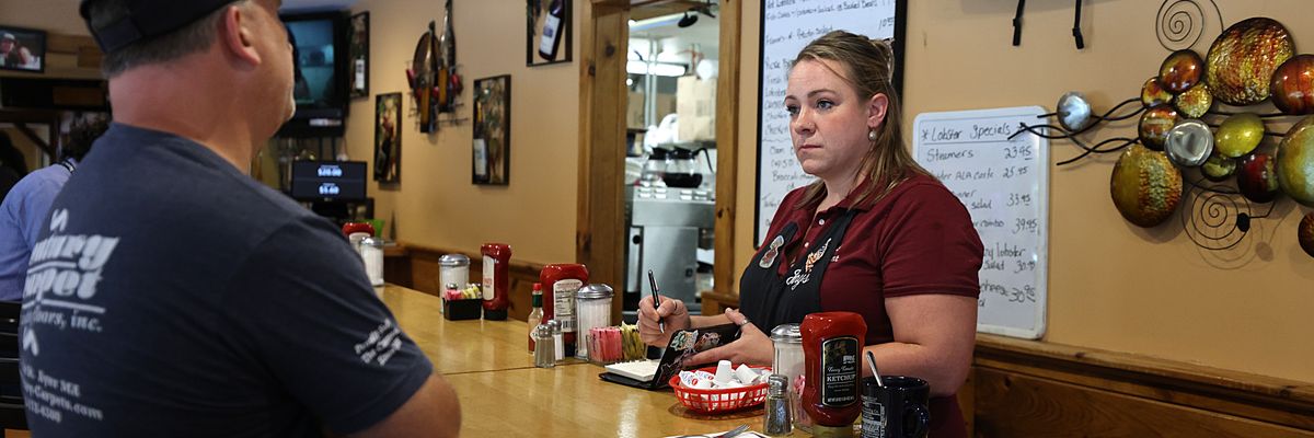 A waitress serves a customer at a counter.