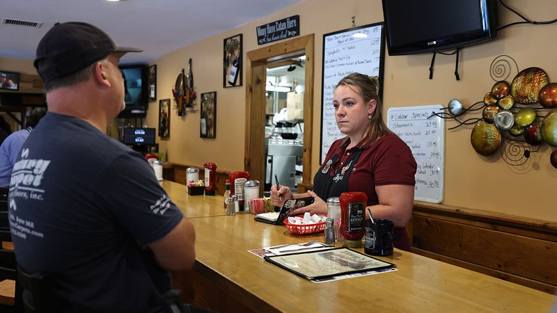 A waitress serves a customer at a counter.