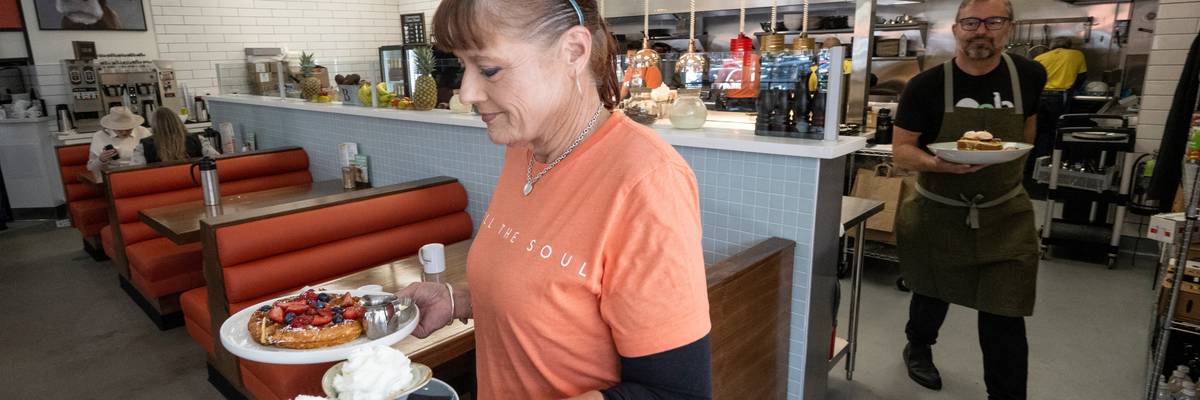 A waitress serves a meal at OEB Breakfast Co.