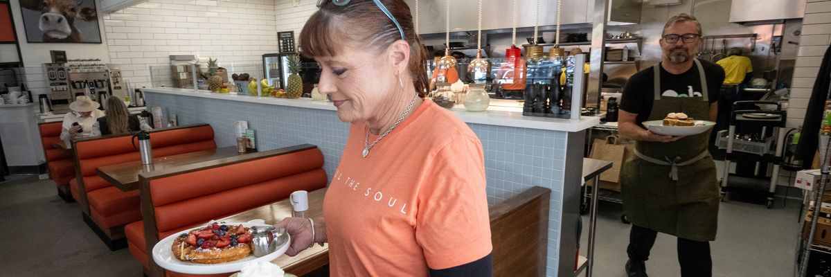 A waitress serves a meal at OEB Breakfast Co.