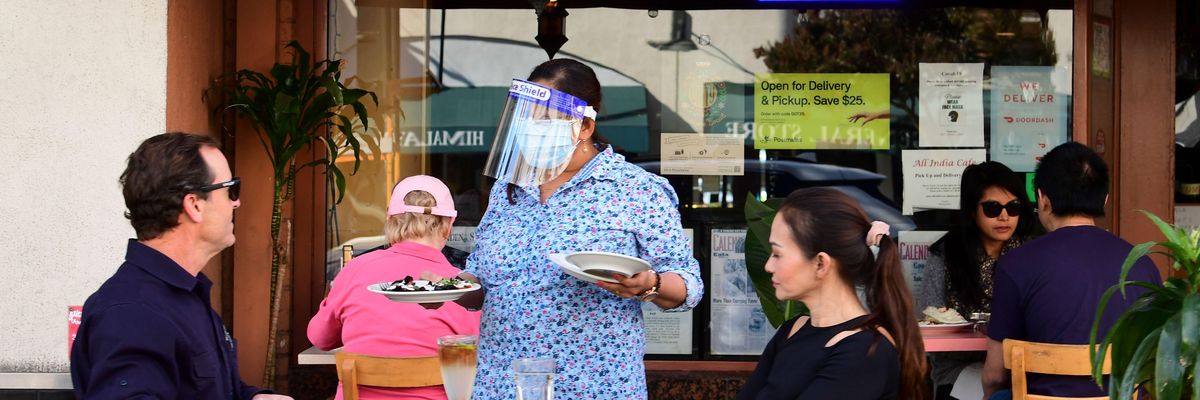 A waitress serves guests as people dine outdoors in Pasadena, California on December 2, 2020.
