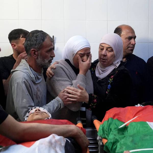 A weeping, grieving Palestinian woman is consoled over the bodies of a man and boy killed by Israeli forces