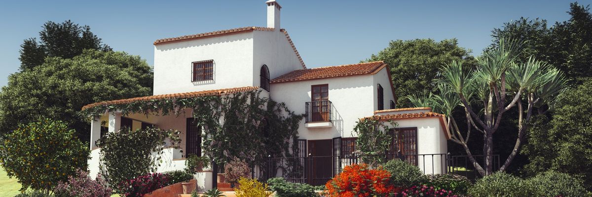 A white Mediterranean-style villa with red roofs and vines. 