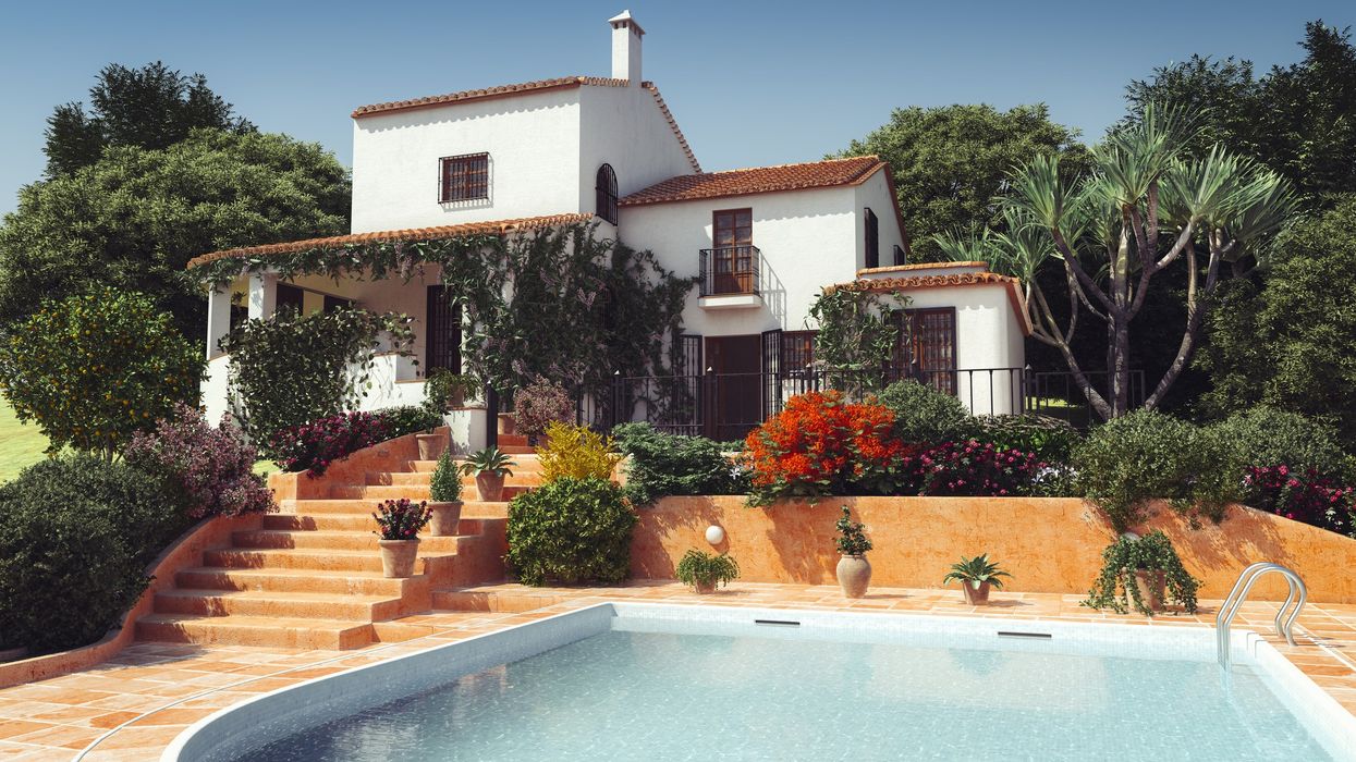 A white Mediterranean-style villa with red roofs and vines.
