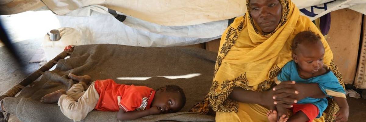 A woman and children are seen in a tent at a center for displaced people in sudan