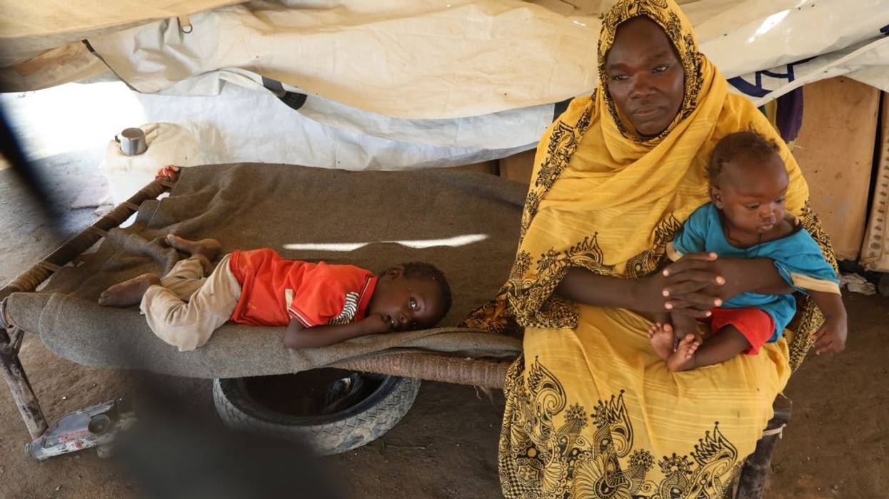 A woman and children are seen in a tent at a center for displaced people in sudan