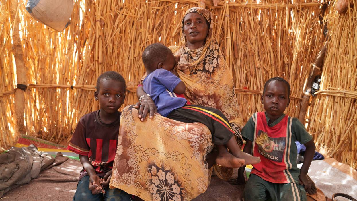 A woman and her children sit in a shack at a displacement camp near the border town Al-Tina in western Sudan
