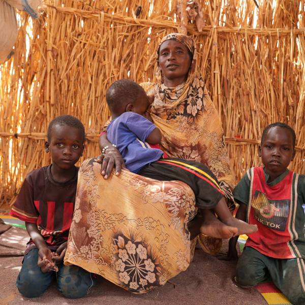 A woman and her children sit in a shack at a displacement camp near the border town Al-Tina in western Sudan