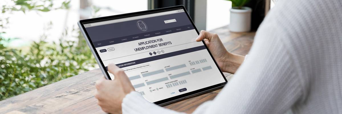 A woman applies for unemployment benefits on a tablet.