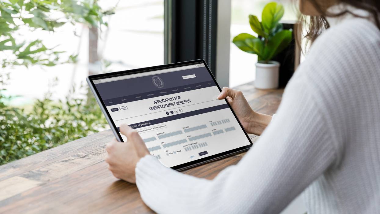 A woman applies for unemployment benefits on a tablet.