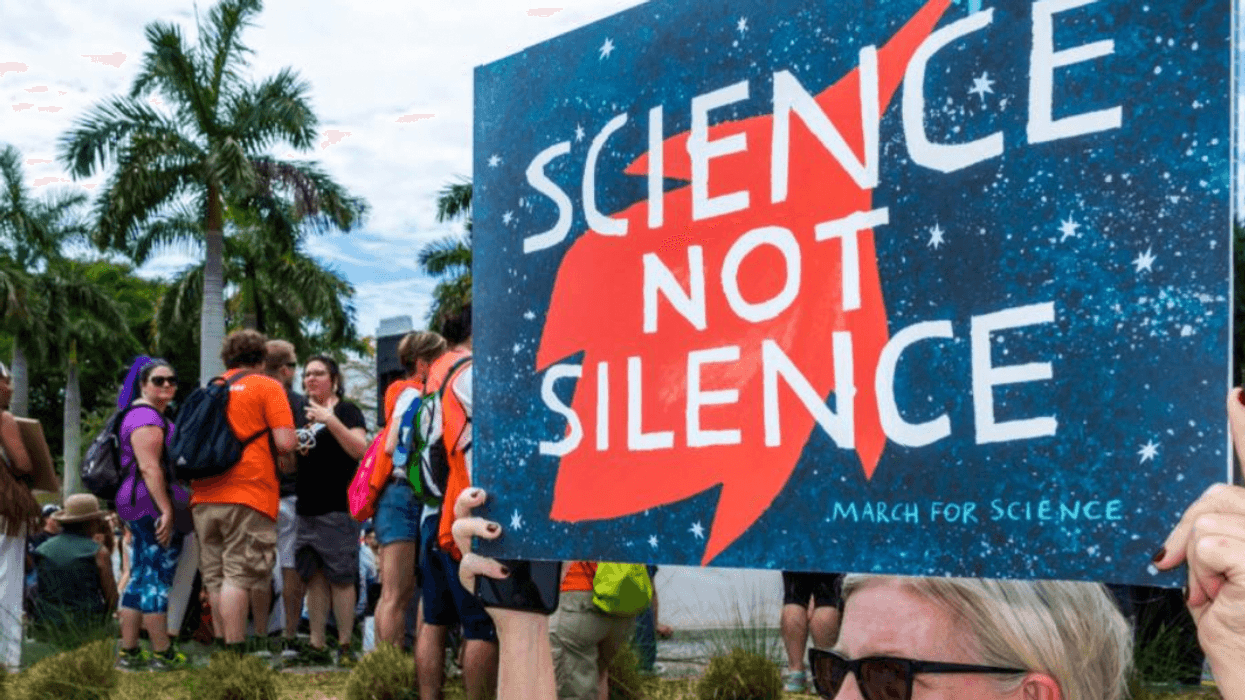 A woman carries a sign reading "Science not Silence"