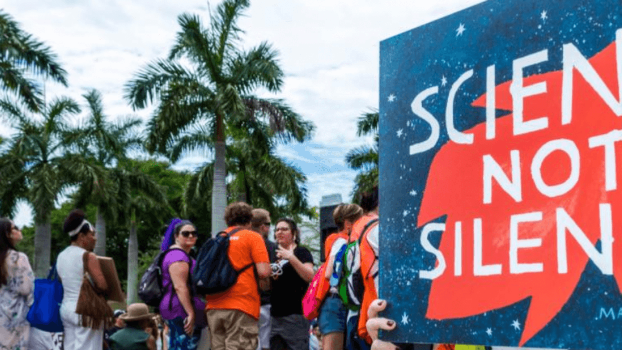 A woman carries a sign reading "Science not Silence"