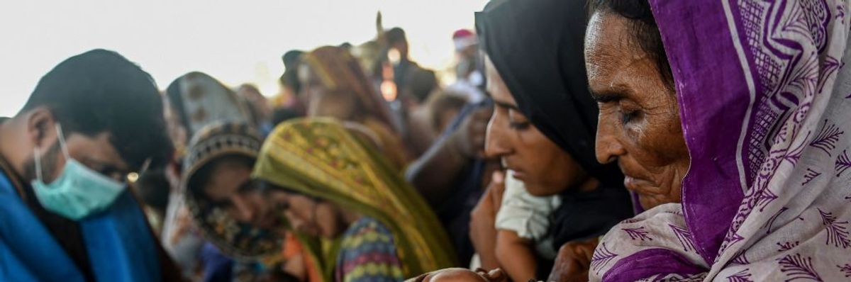 A woman carrying a child while awaiting relief in flood-damaged Pakistan