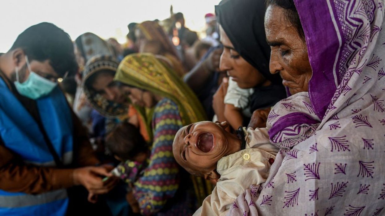 A woman carrying a child while awaiting relief in flood-damaged Pakistan