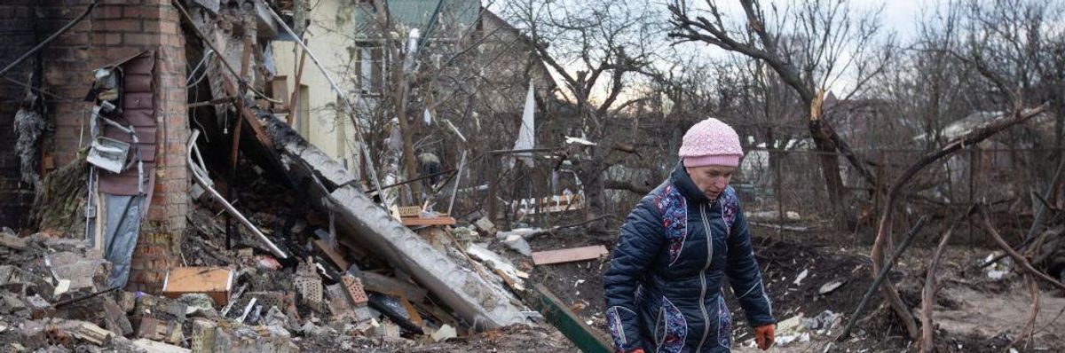 A woman cleans up rubble from a house destroyed by a Russian missile in a village on the outskirts of Kyiv, Ukraine