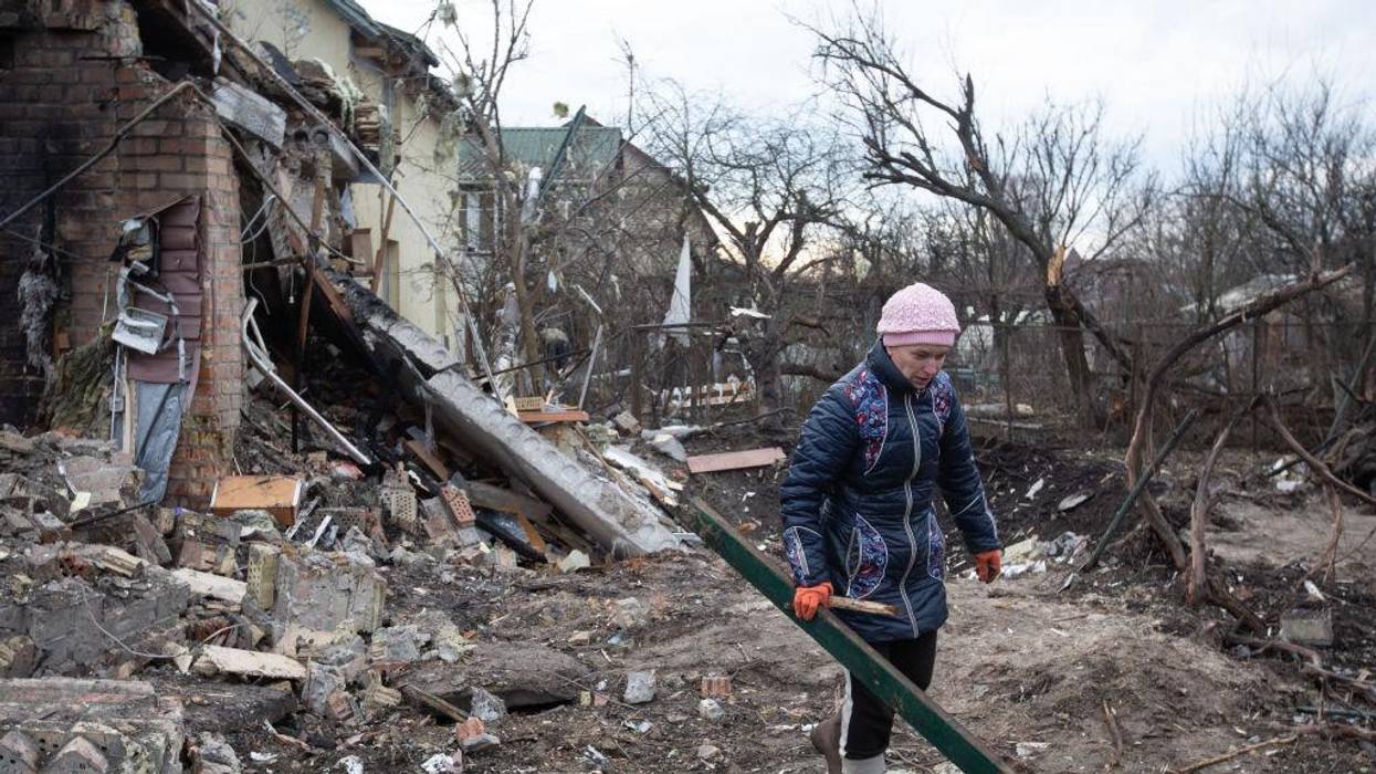 A woman cleans up rubble from a house destroyed by a Russian missile in a village on the outskirts of Kyiv, Ukraine