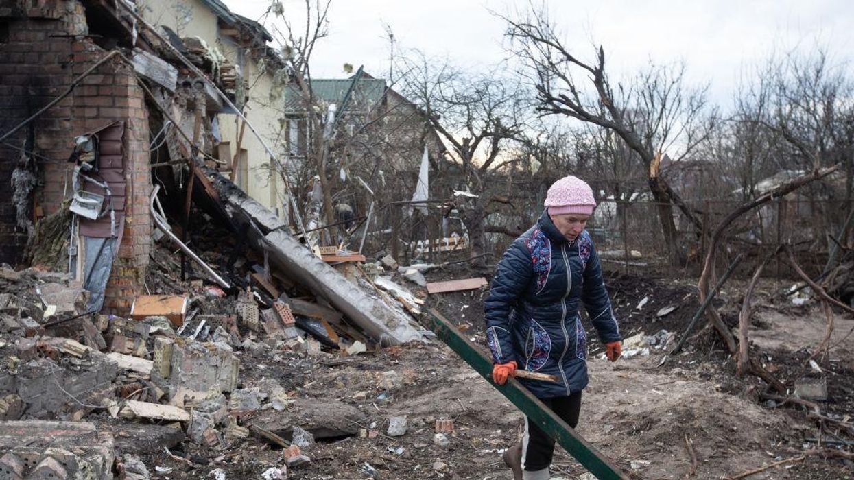 A woman cleans up rubble from a house destroyed by a Russian missile in a village on the outskirts of Kyiv, Ukraine