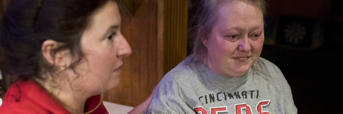 A woman comforts another over returning cancer.