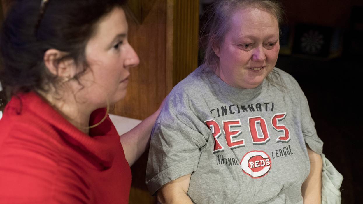 A woman comforts another over returning cancer.