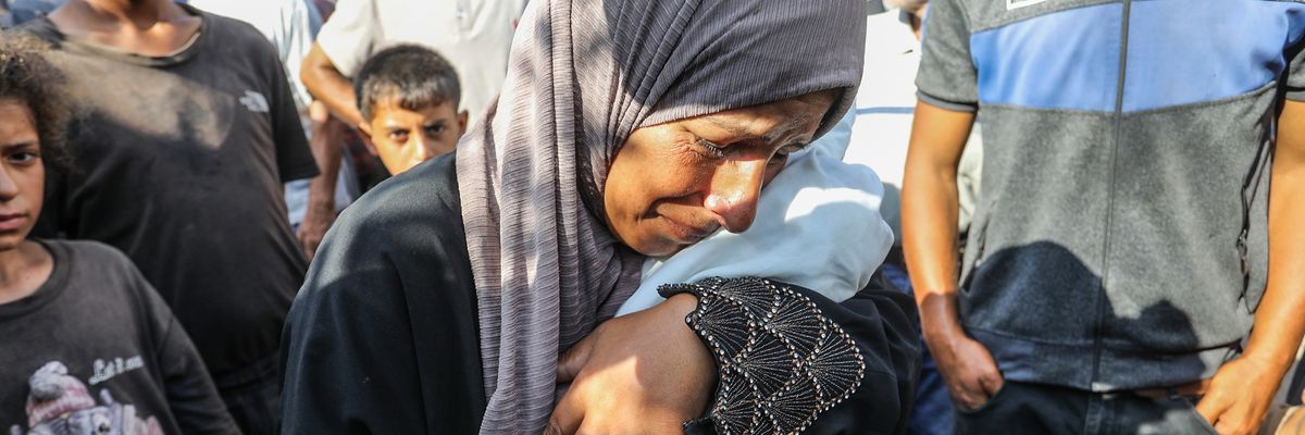 A woman cries as she hugs the tiny starved body of four-month-old Yahya al-Najjar