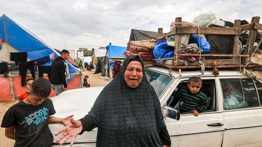 A woman cries as she stands before a vehicle loaded with items