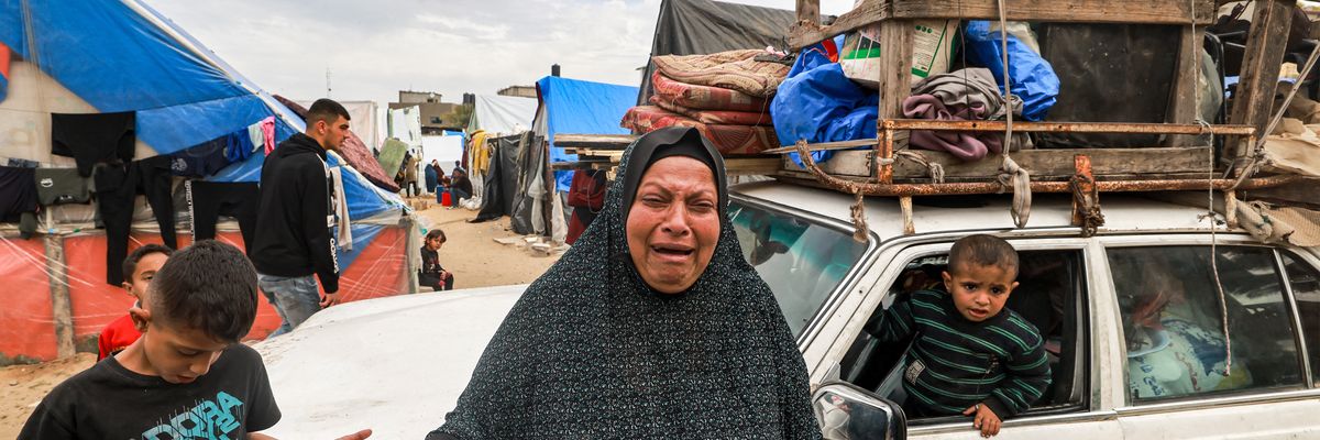 A woman cries as she stands before a vehicle loaded with items