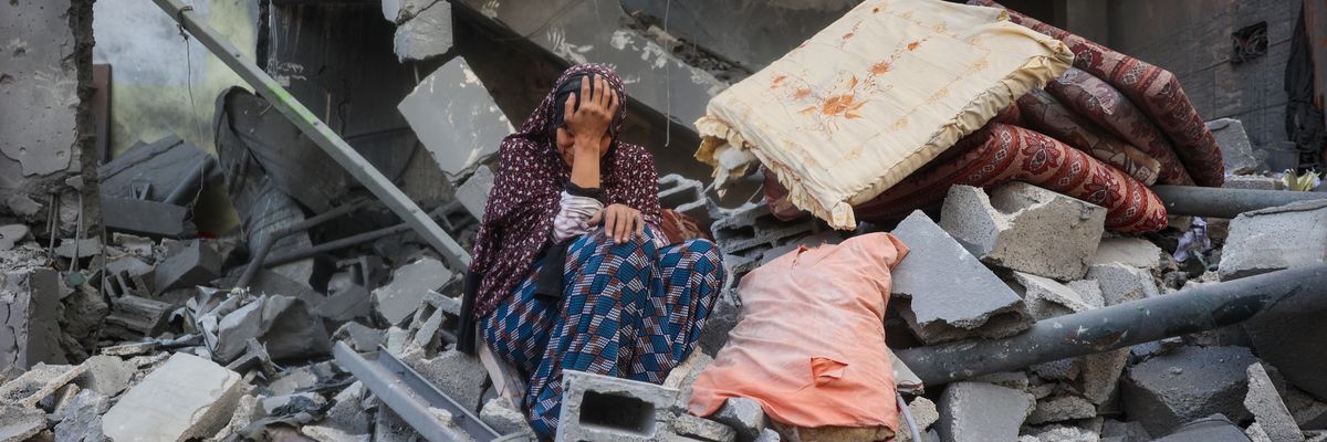 A woman cries while sitting on the rubble of her house