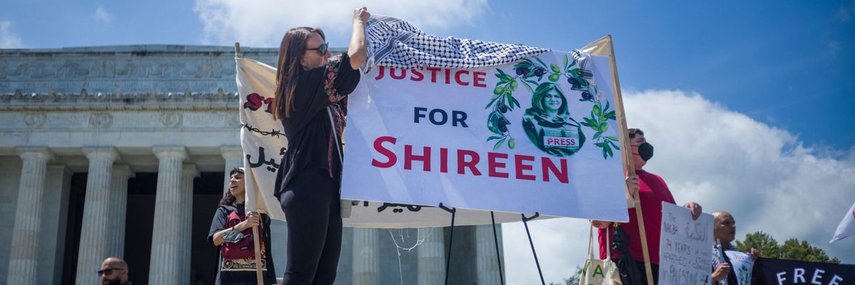 A woman drapes a keffiyeh on a banner calling for justice for slain Palestinian American journalist Shireen Abu Akleh